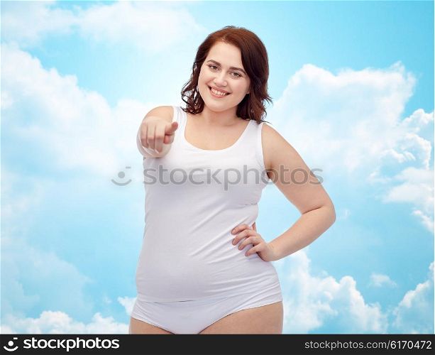 gesture, weight loss and people concept - smiling young plus size woman in underwear pointing finger to you over blue sky and clouds background