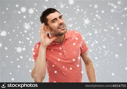gesture, winter, christmas and people concept - man having hearing problem listening to something over snow on gray background
