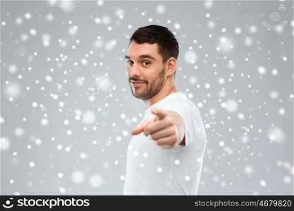 gesture, winter, christmas and people concept - man pointing finger to you over snow on gray background