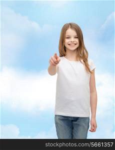 gestures and happy people concept - happy little girl in blank white t-shirt pointing at you