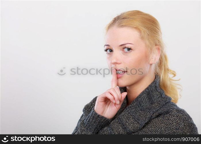 Gestures, symbols of quiet concept. Portrait, blonde adult woman holding finger close to lips gesturing silence. Woman holding finger close to lips, silence