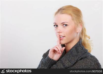 Gestures, symbols of quiet concept. Portrait, blonde adult woman holding finger close to lips gesturing silence. Woman holding finger close to lips, silence