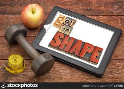 get in shape motivation fitness concept - text in vintage letterpress wood type on a digital tablet, with a dumbbell, apple and tape measure