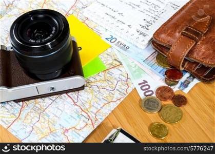 getting ready for travel, money, map and photo camera on wooden table with copy space