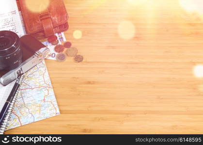 getting ready for travel, money, map and photo camera on wooden table with copy space