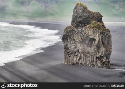 Giant Rock in Reynisfjara Black Beach on a cloudy summer morning, Iceland.