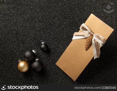 gift booklet with Christmas tree decorations on a black grainy background. flyer with ribbon on black grainy background. booklet with a christmas tree toy on the sand