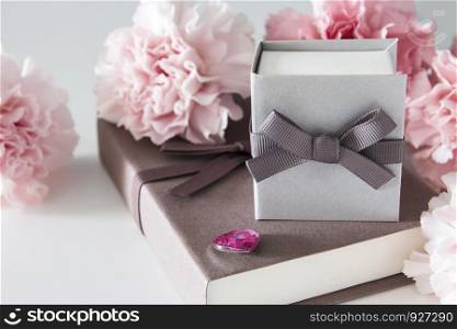 Gift box and carnation flowers on white background