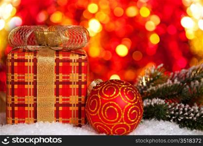 Gift box and Christmas tree decorations in snow on lights background
