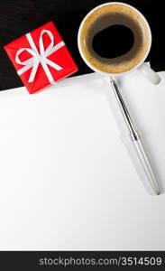 gift box and coffee cup with notepad on dark table