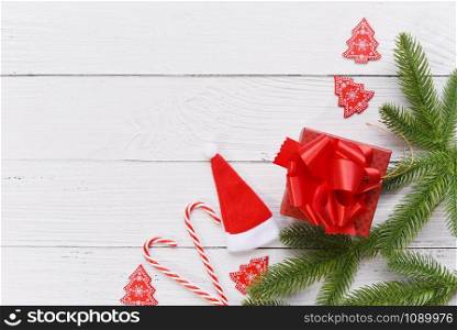 Gift box and Festive Happy New Year object / Christmas holiday background with Santa hat and fir branches decoration candy cane , top view copy space