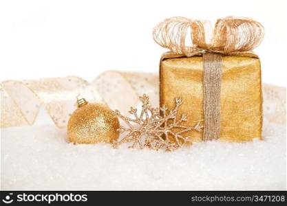 Gift box and gold decorations in snow on white background. Christmas concept. Shallow depth of field