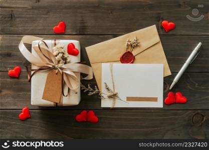 Gift box and greeting card with bow ribbon and paper hearts on wooden table for Valentines day. copy space.