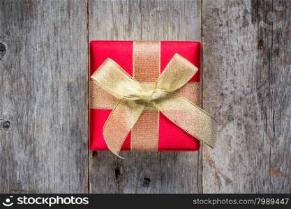 Gift box golden red bow on wood background, top view