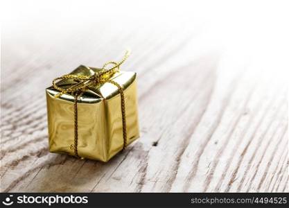 Gift box on wooden background. One small golden gift box on wooden background macro