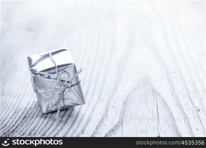 Gift box on wooden background. One small silver gift box on wooden background macro