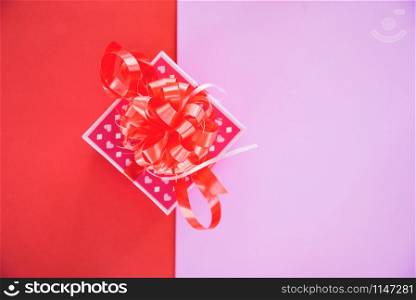 Gift Box pink top view copy space / present box with red ribbon bow for gift to Merry Christmas Holiday Happy new year or Valentines day on red half pink background