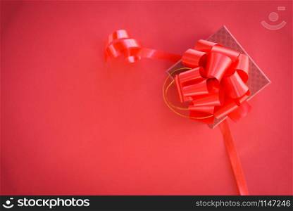 Gift Box red top view copy space / red present box with red ribbon bow for gift to Merry Christmas Holiday Happy new year or Valentines day on red background