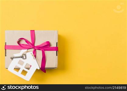 gift box tied with key house model bright yellow background