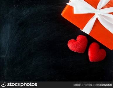 Gift box white bow ribbon and red heart on chalkboard table background top view, february of valentines day in concept.