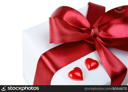 Gift box with a satin red bow and two scarlet hearts