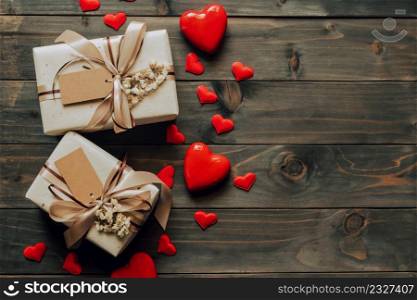 Gift box with bow ribbon and paper hearts on wooden table for Valentines day. copy space.