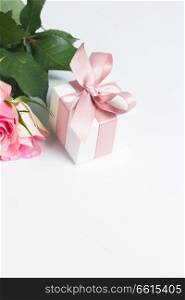 Gift box with pink ribbon with rose flowers on white table with copy space. Box with pink ribbon
