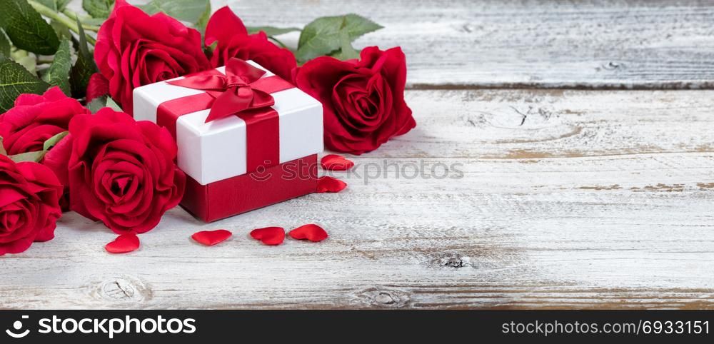 Gift box with red roses and hearts on rustic wood in close up view