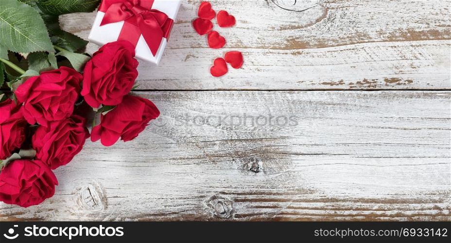 Gift box with red roses and hearts on rustic wood in flat lay view