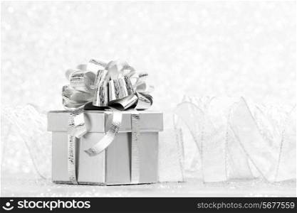 Gift box with tied to bow satin ribbon over bokeh background