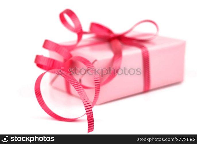 Gift box wrapped in pink wrapping paper and red curly ribbon isolated on white background.