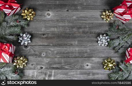 Gift boxes, golden and silver bows plus snow fir branch decorations on rustic wooden planks for a merry Christmas or happy New Year holiday celebration concept