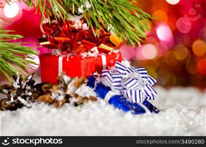 gift boxes on snow with christmas tree branch on blurred background