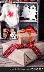Gift boxes with bow on background of decorations with mittens and Christmas trees in the box. Winter decoration with gifts