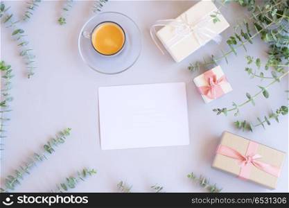 Gift boxes with green leaves. Green leaves with gift boxes with coffee on blue table from above with copy space on paper note , flat lay scene