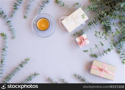 Gift boxes with green leaves. Green leaves with gift boxes with coffee on blue table from above with copy space, flat lay scene