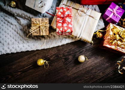 Gift boxes with ornaments on brown wooden, gray knitted background. space for text, design. Happy Holidays. top view. flat lay. stylish wrapped gifts. merry christmas, new year concept. birthday.