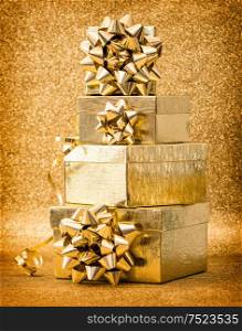 Gift boxes with ribbon bow on golden shiny background. Holidays decoration. Vintage style toned picture