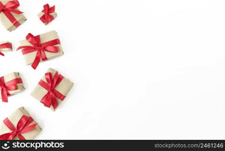 Gift boxes wrapped in craft paper with red ribbons and bows on white background. Festive flat lay with copy space.. Gift boxes wrapped in craft paper with red ribbons and bows on a white background. Festive flat lay with copy space.