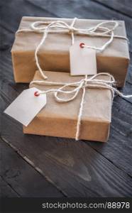 Gift boxes wrapped with white flax string and vintage brown paper, with blank labels attached, displayed on an old wooden table.