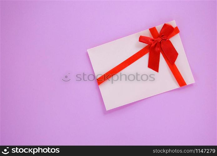 Gift card on red and pink background / Gift card decorated with red ribbon bow to Merry Christmas Holiday Happy new year or Valentines day Gift voucher on pink background top view