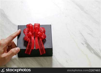 gift giving,man hand holding a gift box in a gesture of giving on white gray marble table background