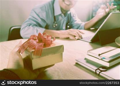 Gift Giving.Patient hand or Team giving a gift to a surprised Medical Doctor in hospital office,vintagefilm effect