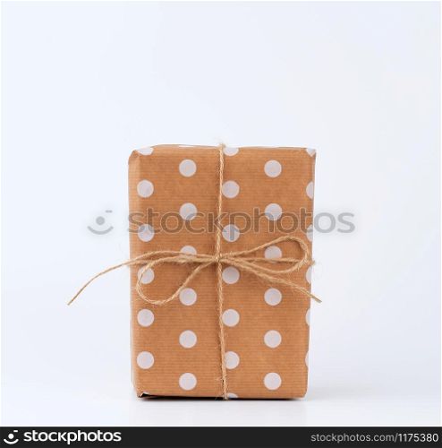 gift in box wrapped in brown kraft paper and tied with rope on a white background. Festive concept, copy space