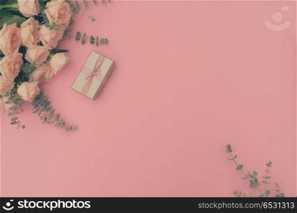 gift or present box and flowers on pink table with rose flowers from above, flat lay frame, retro toned. gift or present box and flowers. gift or present box and flowers