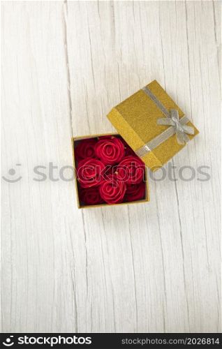 Gift or present box gold with roses flower in the present on white wooden table top view. Flat lay styling close up with copy space, romantic Valentines Day, Mothers Day birthday concept space for text. Gift or present box gold with roses flower in the present on white wooden table top view. Flat lay styling close up with copy space, romantic Valentines Day, Mothers Day birthday concept