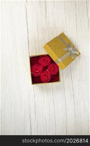 Gift or present box gold with roses flower in the present on white wooden table top view. Flat lay styling close up with copy space, romantic Valentines Day, Mothers Day birthday concept space for text. Gift or present box gold with roses flower in the present on white wooden table top view. Flat lay styling close up with copy space, romantic Valentines Day, Mothers Day birthday concept