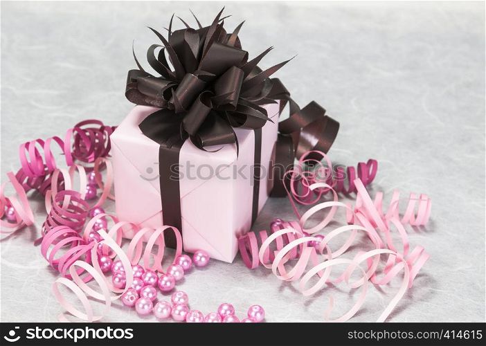 Gift pink box with ribbons, beads and a brown bow