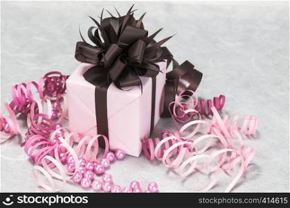 Gift pink box with ribbons, beads and a brown bow