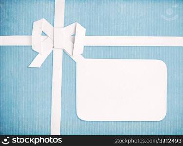 Gift ribbon and bow with blank gift tag, blue retro background